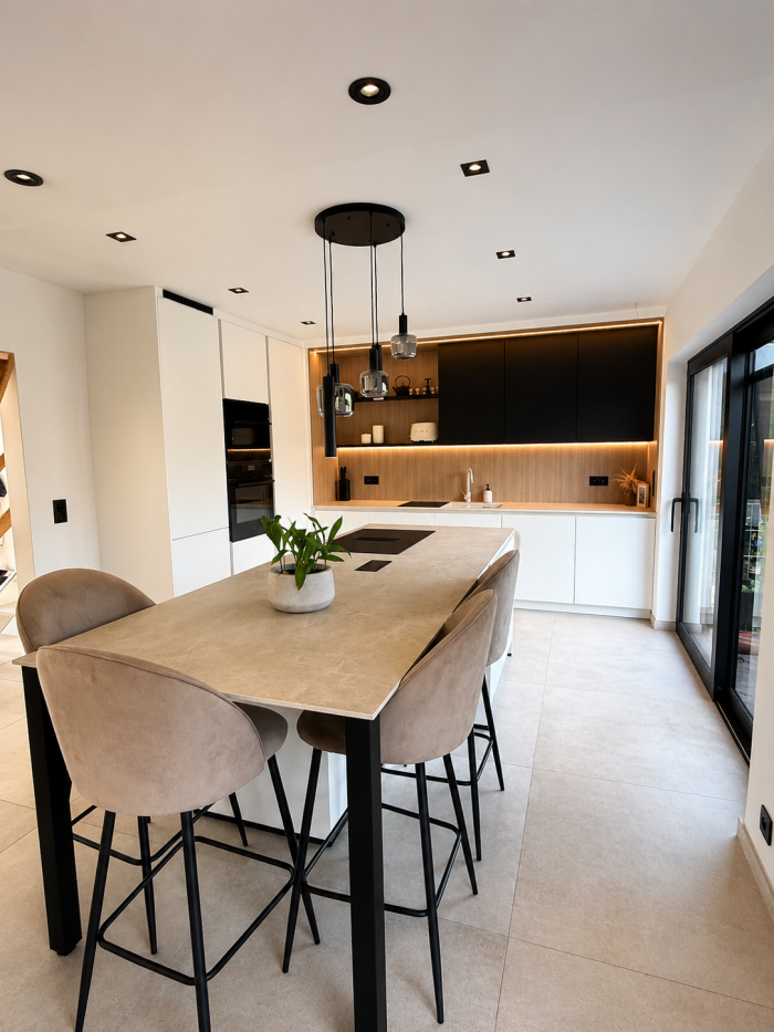 Cette cuisine ouverte mélange parfaitement le moderne et le chaleureux. Avec son grand îlot central, elle est idéale pour cuisiner, partager un repas ou simplement passer un bon moment en famille ou entre amis.  Le mélange du blanc, du bois et du noir don